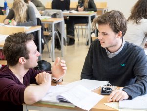 Een docent geeft hulp aan een leerling bij SSL, De Leidse Examentraining