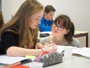 Leerling wordt geholpen door een docent bij de examentraining bedrijfseconomie SSL. 