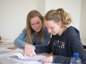 Een docent helpt een leerling met economie bij de examentraining van SSL